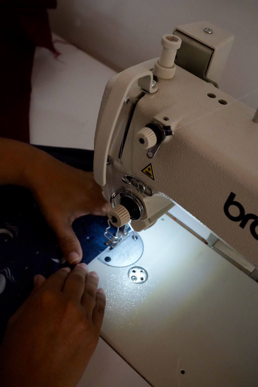 Manos cosiendo en máquina plana
